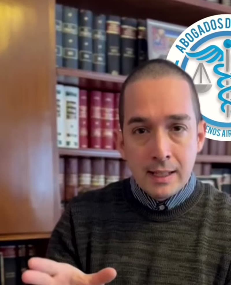 El Dr. Ghiraldo hablando, sentado frente a una biblioteca de libros jurídicos.